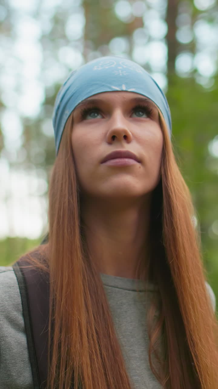 mujeres caminando a través de un bosque sereno, mujer en bandana azul y sudadera gris mirando atentamente al lado, mientras que su compañero en camisa verde está suavemente borroso detrás