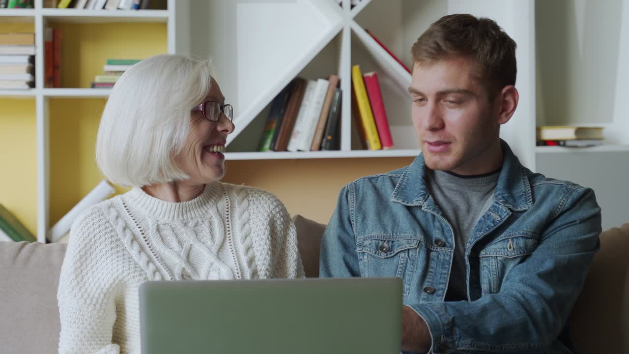 Man teaching his mother using laptop at home, technology concept