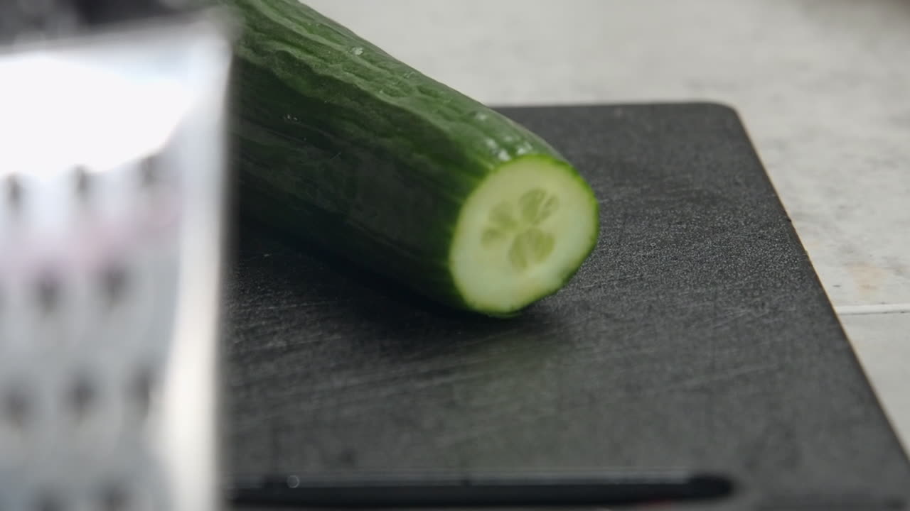 carro de primer plano: punta de pepino cortada en una tabla de cortar de cocina negra