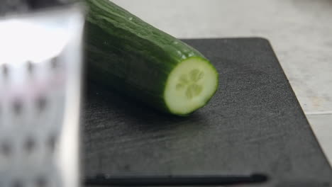 close-up dolly: cucumber tip cut off on black kitchen cutting board