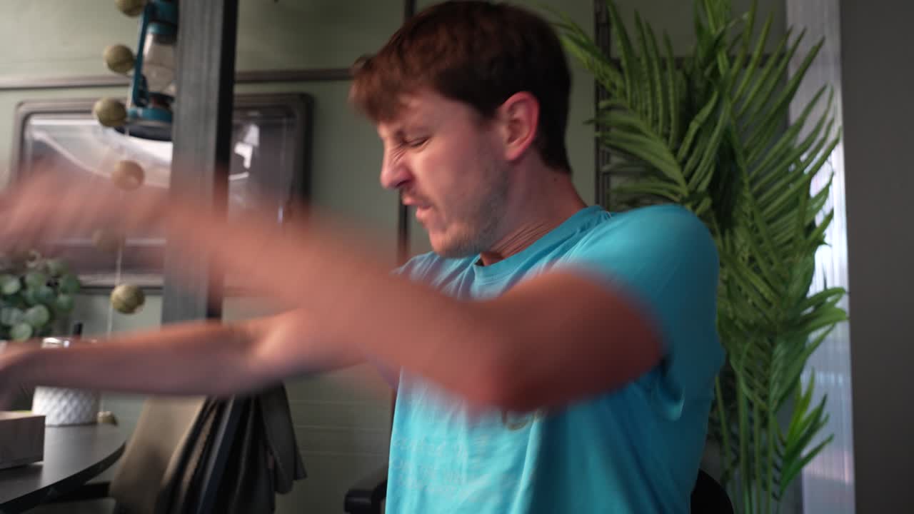 Angry man ends a stressful call: he hangs up, curses at his smartphone, then hurls it aside in a burst of rage, capturing raw frustration and tech-related anger in a home interior.