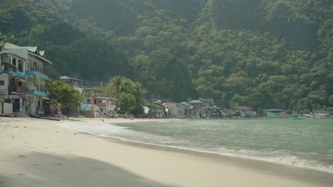 La-Hermosa,-Brillante-Y-Tranquila-Playa-De-El-Nido,-Filipinas,-Con-Habitaciones-De-Resort-Frente-Al-Agua-Y-Las-Montañas-En-El-Fondo---Plano-General