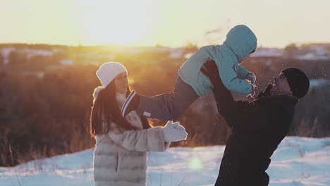 tremendous parents play with toddler son in winter at sunset