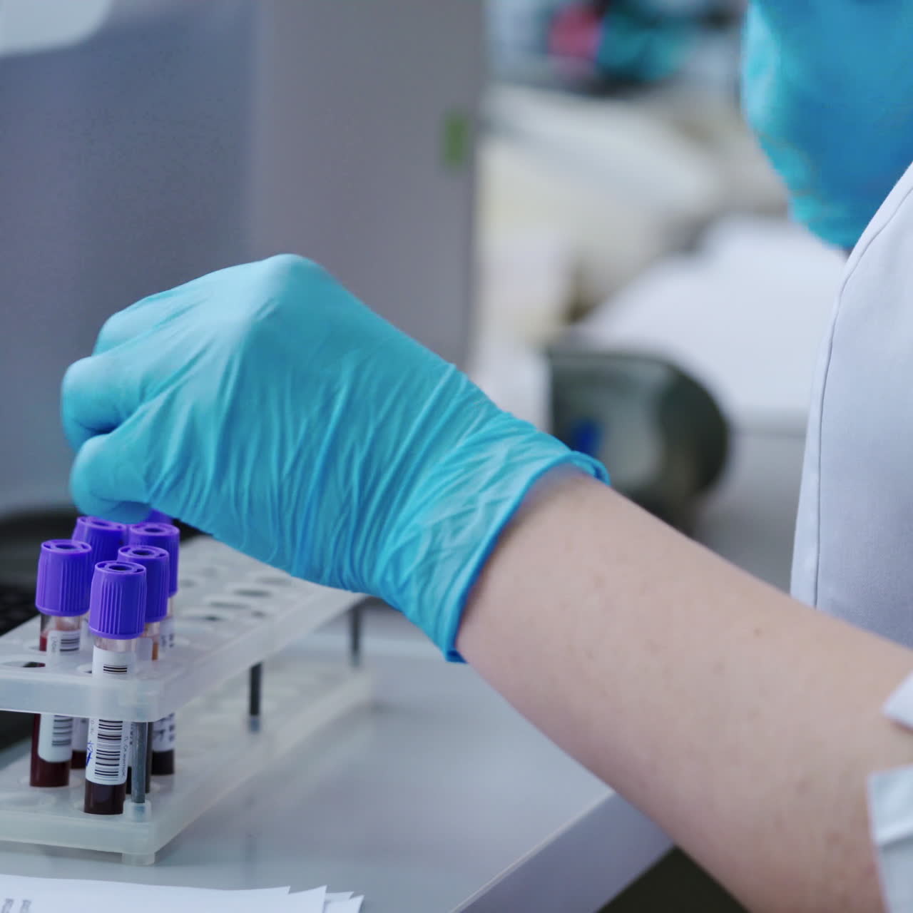 Laboratory worker with blood samples. Woman's hands in sterile gloves working with test tubes on the table in the laboratory. Medical concept.