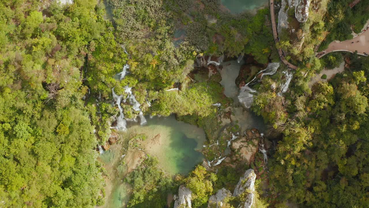 increíble vista aérea de drones de arriba hacia abajo de lagos turquesas brillantes conectados con cascadas entre acantilados rocosos y bosques densos