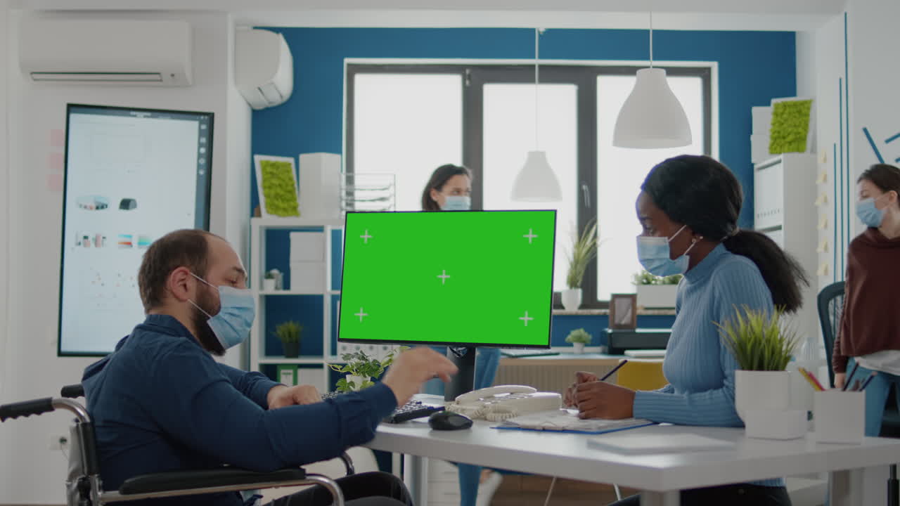 녹색 화면을 가리키는 얼굴 마스크를 입은 장애인 회사 지도자