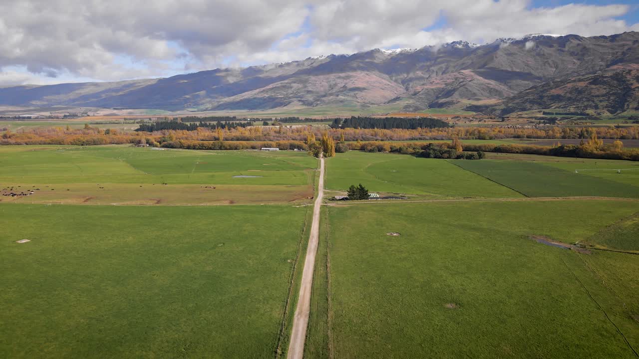 camino recto que conduce hacia el follaje de otoño en la parte inferior de la cordillera