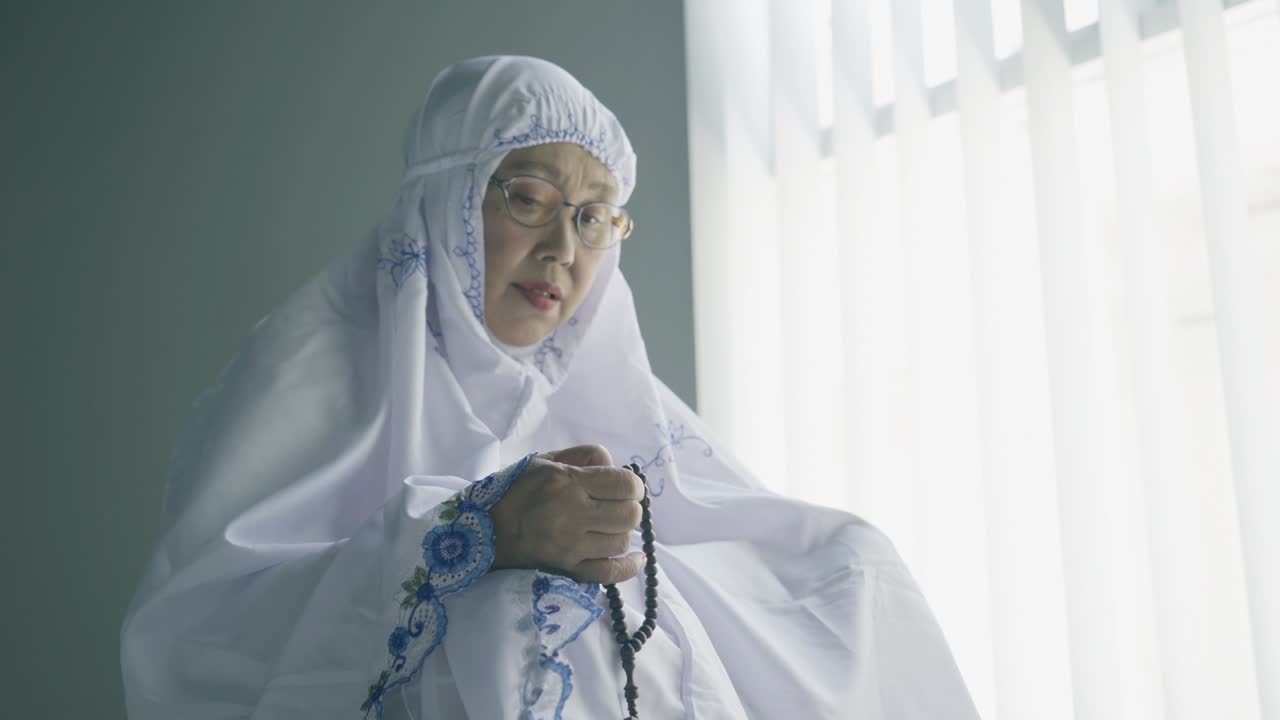 시니어 여성은 사라트를 한 후 지크르를 위해 구슬을 들고 있습니다.