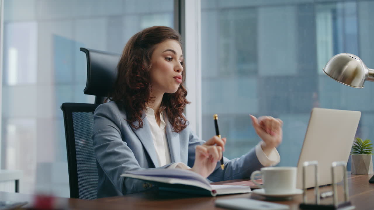 dipendente felice che parla con la telecamera del portatile che ha una videoconferenza seduto in ufficio.