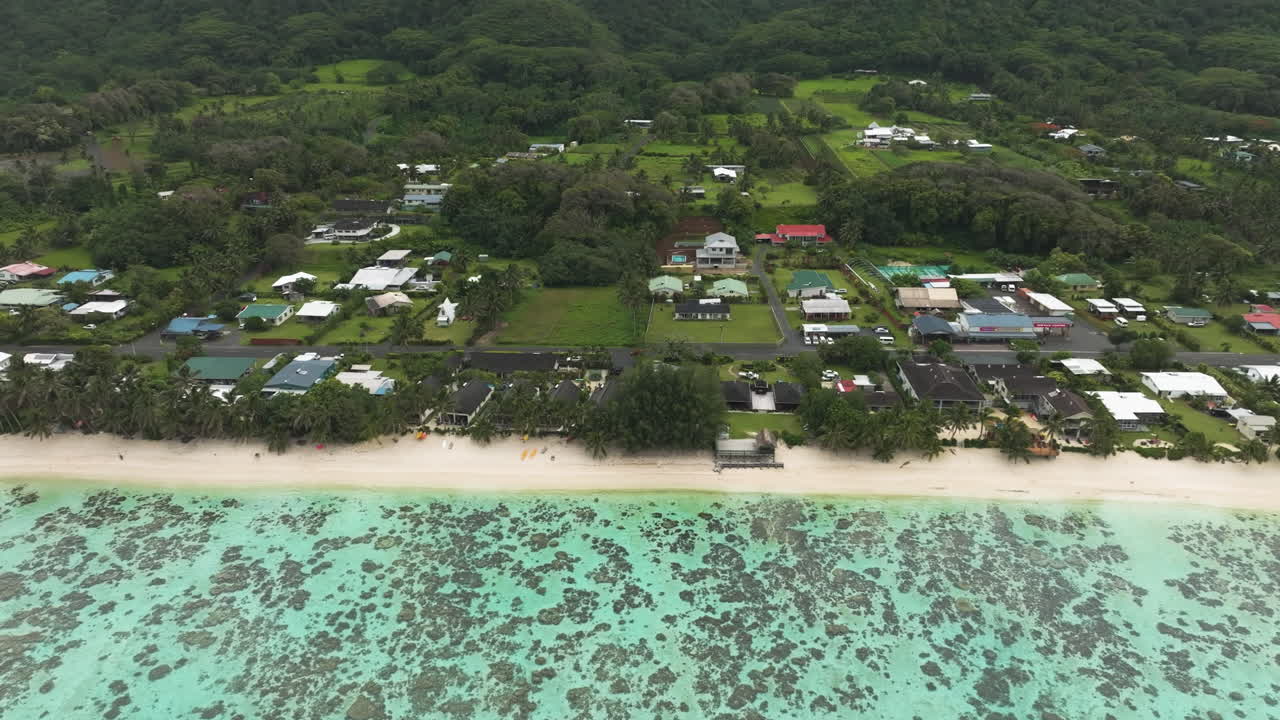 Aerial angled tracking left above coastline with gas station and sandy beach by hotels
