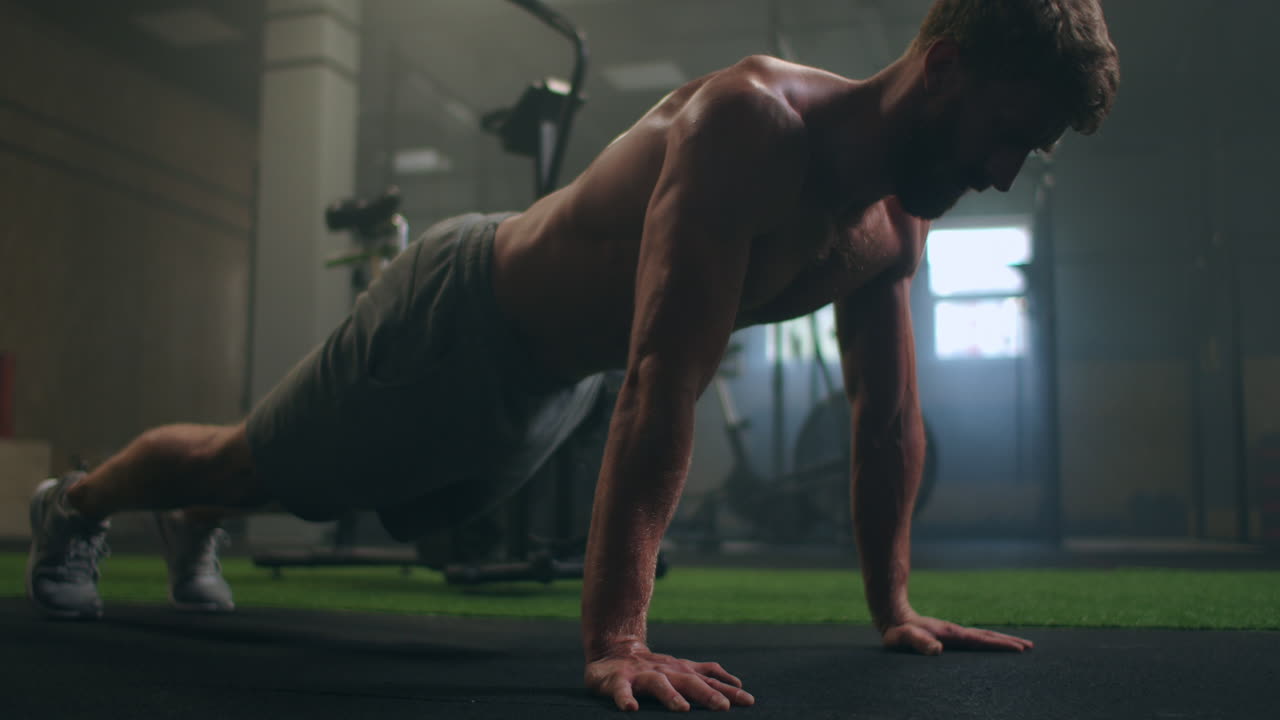 hombre haciendo flexiones en un gimnasio. exhalación e inhalación después de flexiones y ejercicio. perfecto para el acondicionamiento físico y el entrenamiento. joven deportista realiza flexiones en el gimnasio. el atleta está involucrado en fitness