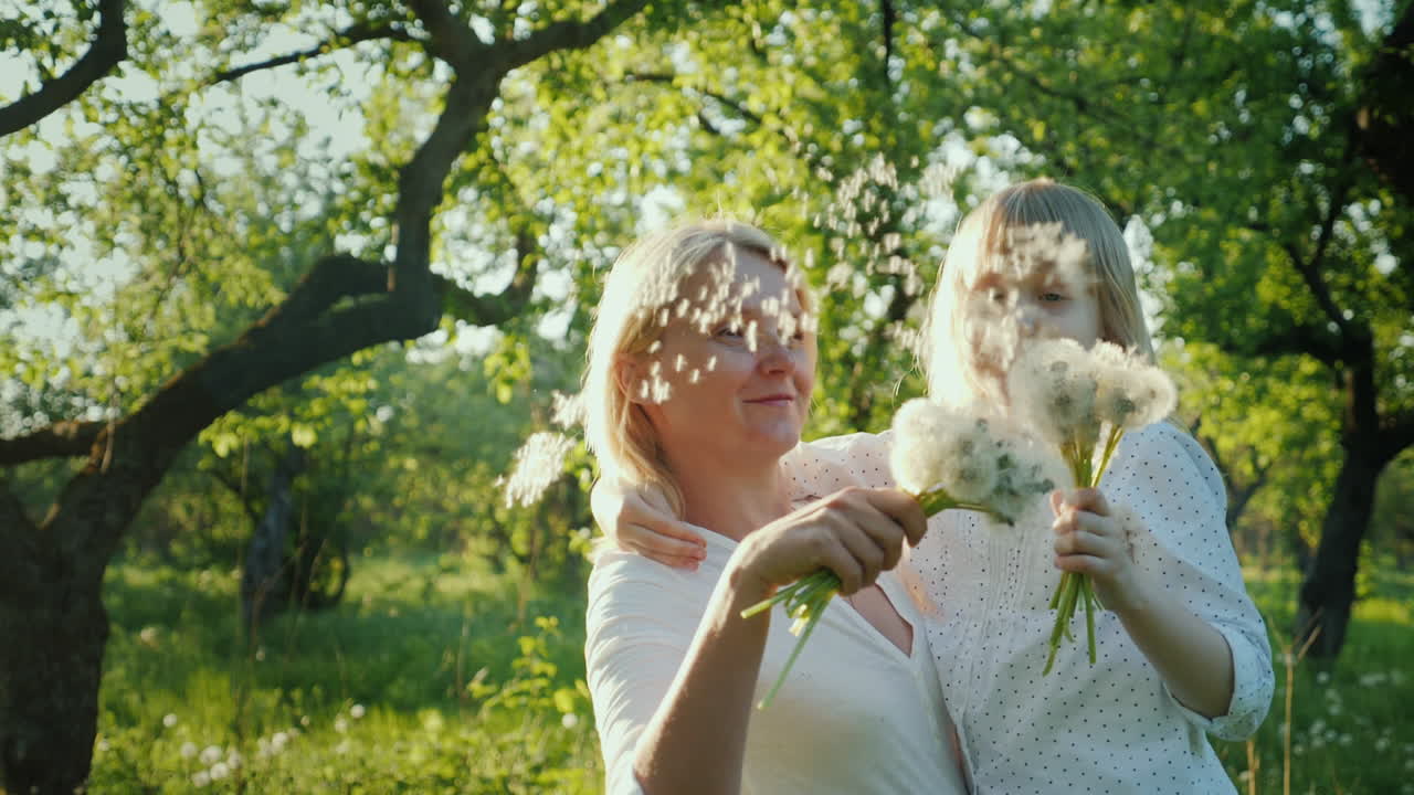행복한 함께 - 민들레 다발을 가지고 노는 딸과 함께 즐거운 시간을 보내는 여성