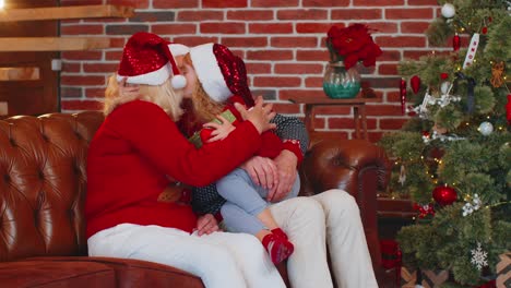 grandfather grandmother gifting christmas present box to amazed happy grandchild girl kid at home