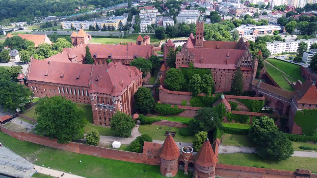 Stunning aerial approach over Malbork Castle, a UNESCO listed medieval fortress in Poland, built in gothic style as cloud shadow passes over top