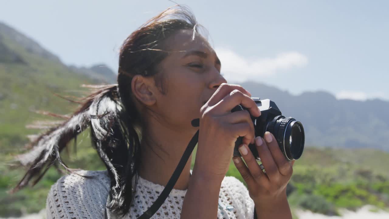아프리카계 미국인 여성 이 산 에서 하이킹 하는 동안 디지털 카메라 로 사진 을 찍고 있다