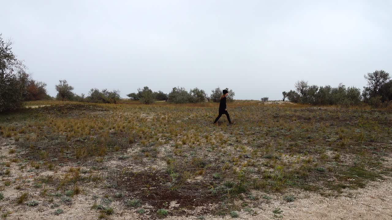 The girl goes on a heathland. Shooting in the fall