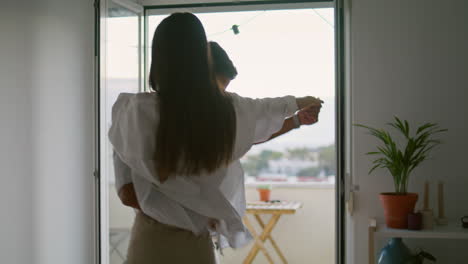 Playful spouses dancing panoramic window apartment. Romantic couple hugging