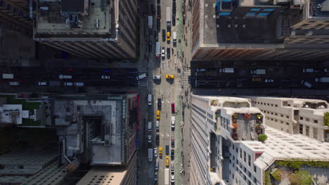 Aerial-birds-eye-overhead-top-down-panning-view-of-slowly-moving-vehicles-in-wide-streets-between-high-rise-buildings-in-city.-Manhattan,-New-York-City,-USA