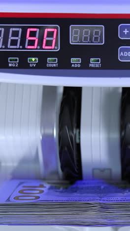money counting equipment for paper money calculation. automatic mechanism for bank financial operations. currency exchange of one hundred dollars. close-up. vertical video