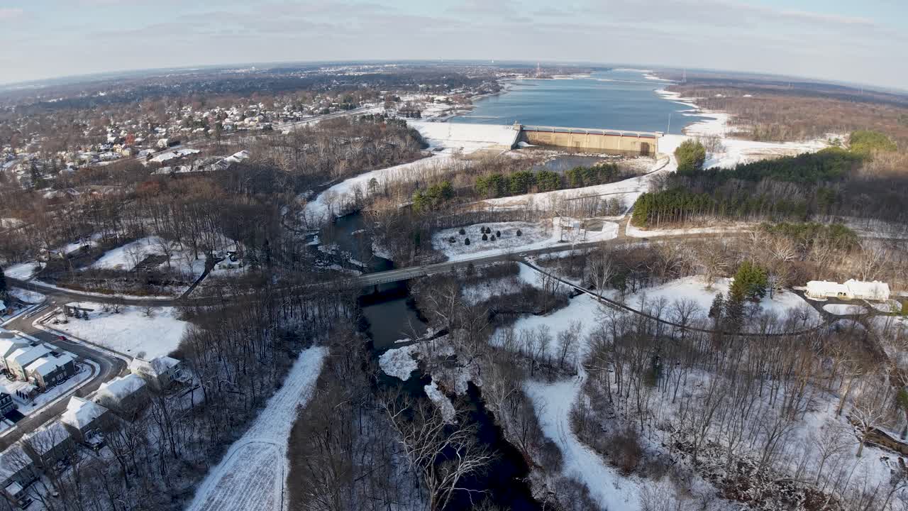 High altitude drone clip captures a narrow ravine and stream cutting through snow covered terrain and residential areas leading toward Hoover Reservoir in Westerville Ohio