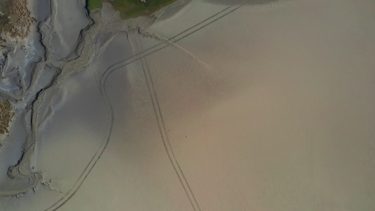 vista de pájaro de una bahía arenosa cuando la marea está baja, mostrando patrones en la línea costera