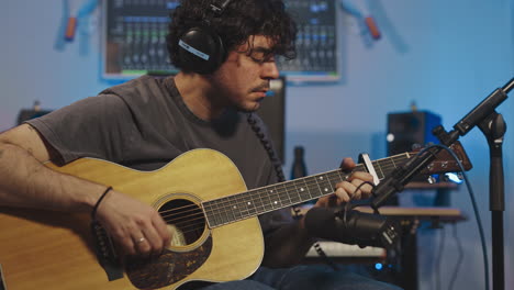 professional musician recoding new album playing acoustic guitar in recording studio