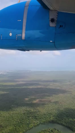 vertical view of plane with turboprop engine flying above landscape of belize, passenger pov