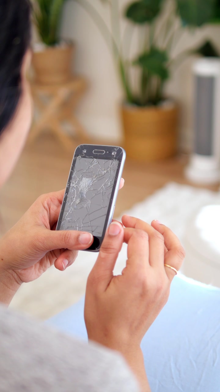 Close-up of Woman's Hands Holding a Smartphone with a Cracked Screen