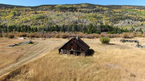 dolly backwards of cabin in field with fall colors in background