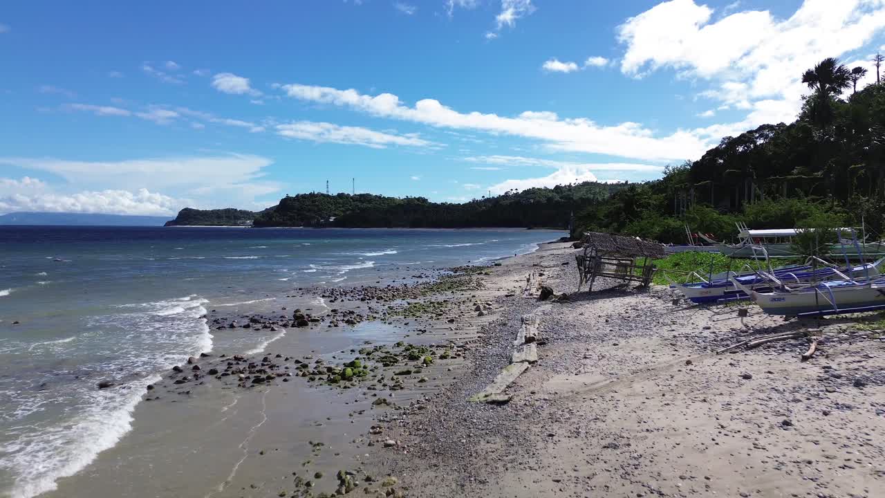 Rekaman drone udara berkualitas tinggi dari Pantai Aninuan di Puerto Galera, Filipina yang menampilkan air sebening kristal, garis pantai berpasir, hutan hijau lebat, dan latar belakang pegunungan