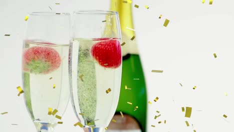 Animation-of-gold-confetti-falling-and-strawberries-dropping-into-in-glasses-of-champagne,-on-white
