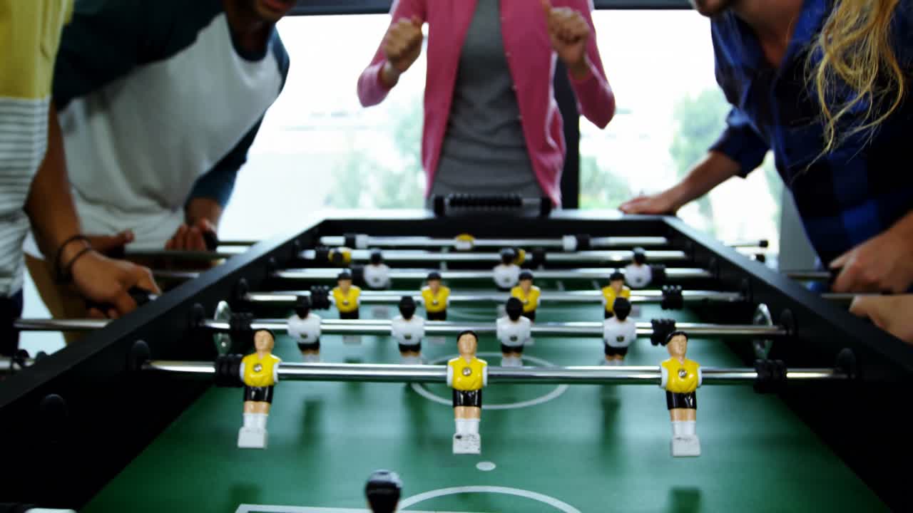 Happy graphic designers playing table football