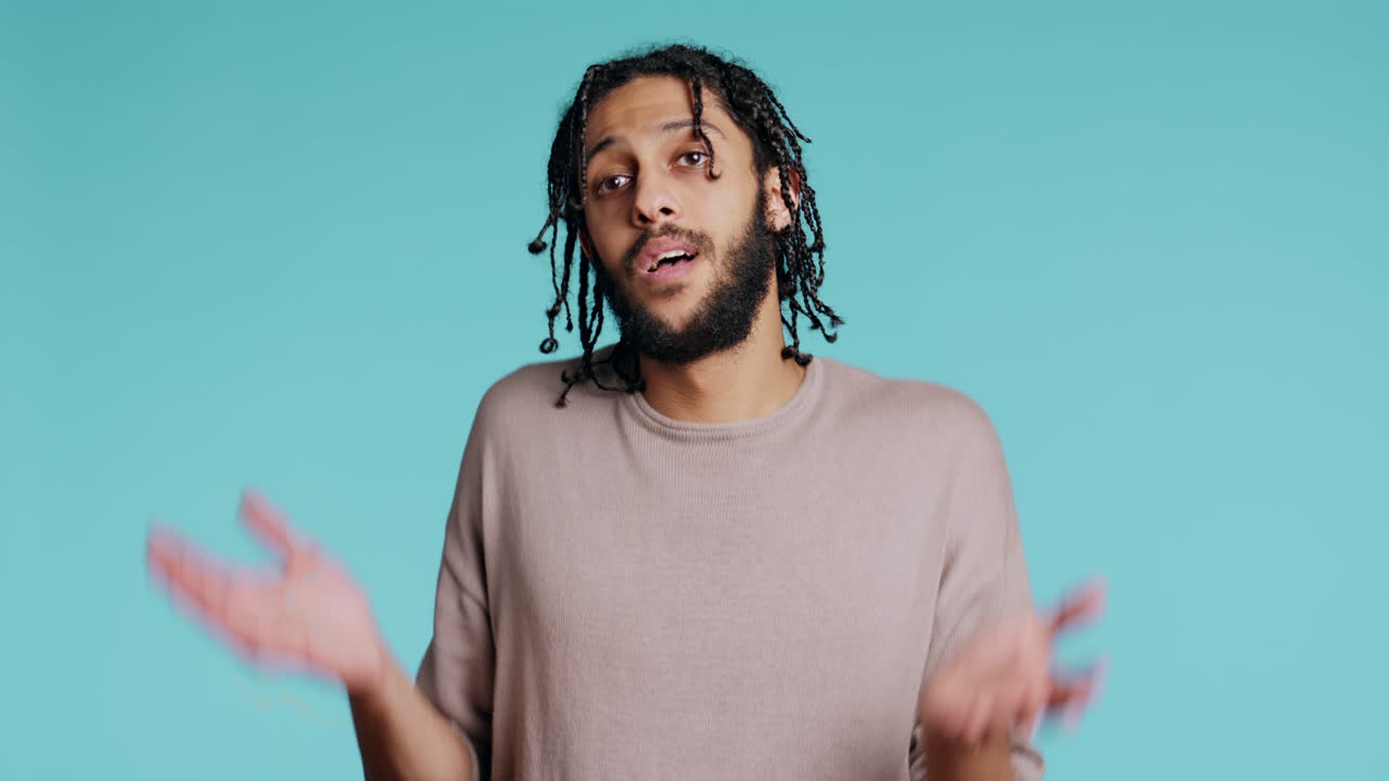 Uncaring man shrugging shoulders, showing indifference, studio background