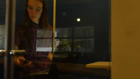 Front-view-of-young-caucasian-businesswoman-talking-on-mobile-phone-while-working-on-laptop-4k