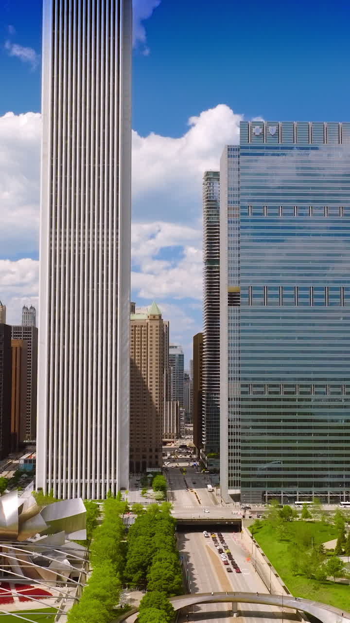 Wide road going through the famous Millennium Park in downtown Chicago. Greenery and metal installations at the backdrop of modern architecture. Vertical video