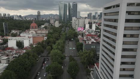 aerial follows traffic on tree lined street leading in mexico city