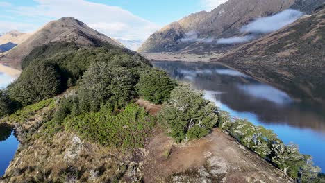 aerial footage captures the serene beauty of lake moke, showcasing lush greenery and reflective waters under clear skies in queenstown