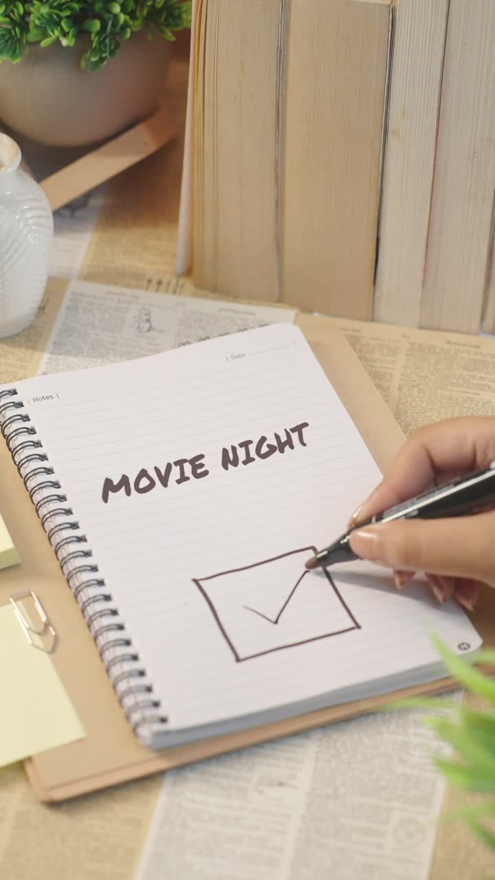 VERTICAL VIDEO OF TICKING OFF MOVIE NIGHT FROM CHECKLIST