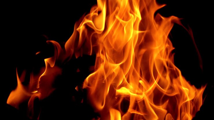 Falò. Il fuoco è acceso nella notte. Fiamme di fuoco su sfondo nero al rallentatore.