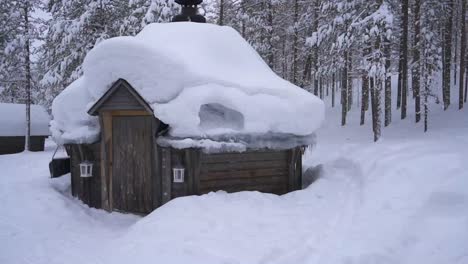 Eine-Gemütliche-Schneebedeckte-Hütte-In-Einem-Ruhigen-Finnischen-Wald,-Umgeben-Von-Schneebedeckten-Bäumen-Und-Einer-Friedlichen-Winterlandschaft,-Die-Die-Schönheit-Eines-Ruhigen-Winterresorts-Zeigt