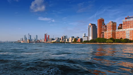 waves go from a boat traveling by the river. low angle view at the skyline of new york on sunny day