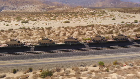 aerial view hundreds of american army tanks being transported through the desert by train