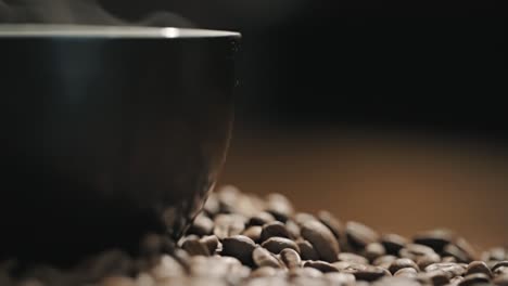 vapor sobre una taza de café en una mesa de madera rodeada de granos de café frescos a cámara lenta