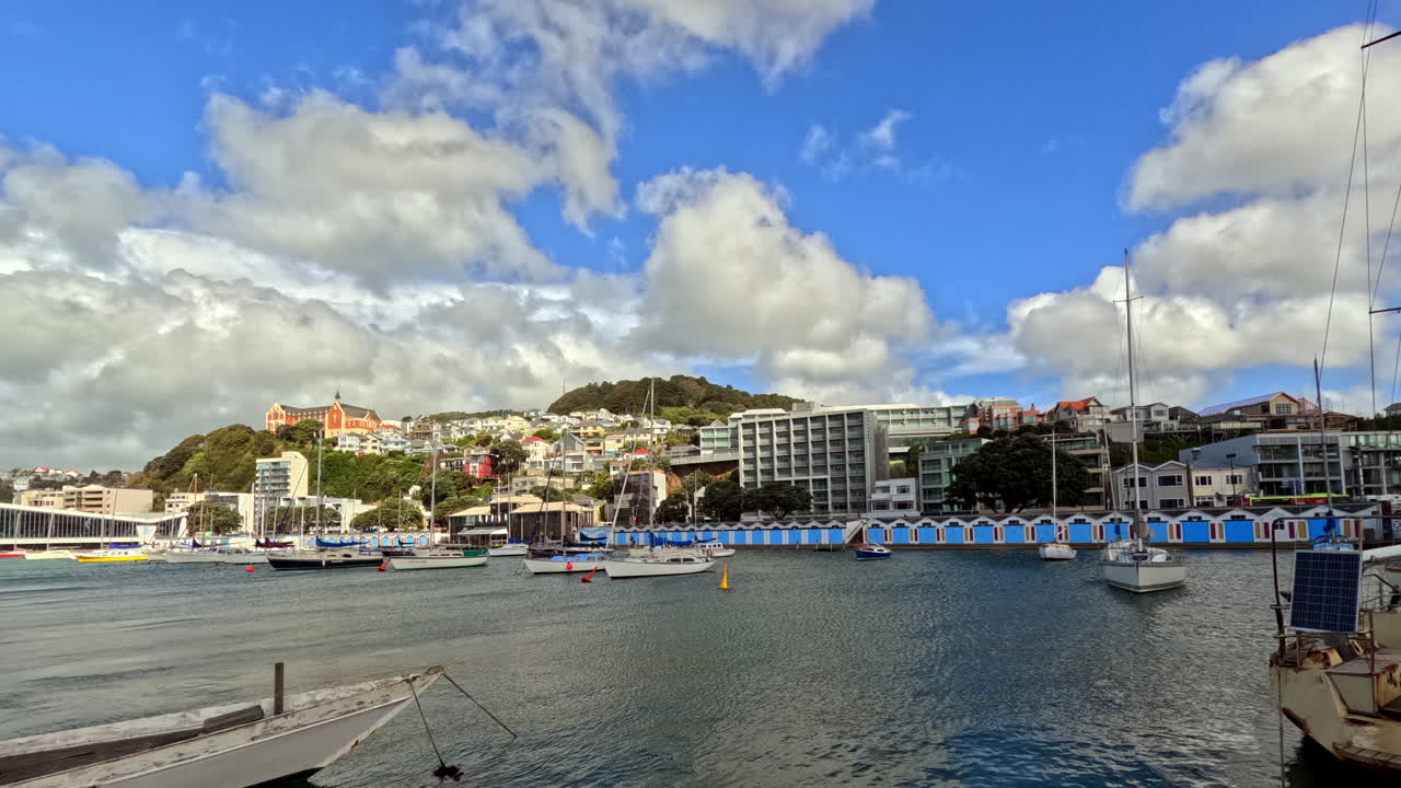 waterfront captures the colourful boat sheds of Wellington’s Oriental Bay with yachts gently moored in the turquoise harbor Above the shoreline, a patchwork of homes and buildings rises into the hills