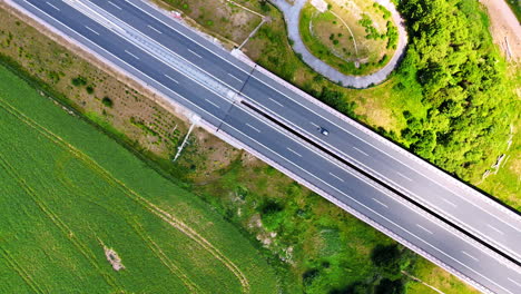 truck on highway by fields. a white truck moves swiftly on a wide highway surrounded by lush green fields and trees, showcasing natural beauty