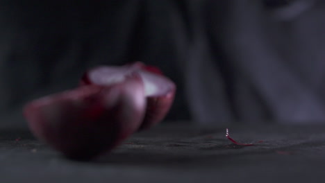 cutting an red onion on a black cutting board.