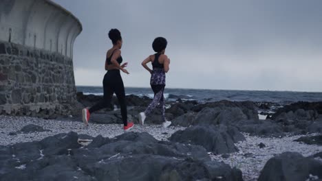 Zwei-Gemischtrassige-Frauen-Laufen-Am-Strand