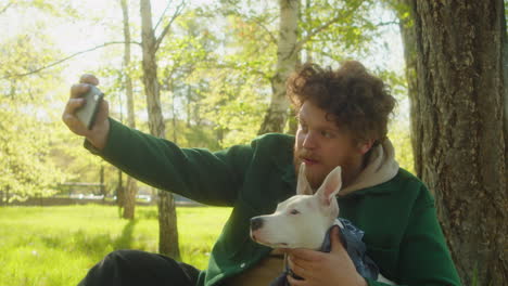 man taking selfie with dog in park