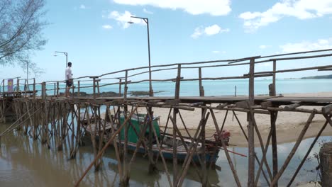 wooden jetty bridge, male tourist standing, enjoying vacation, thailand