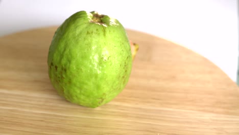 guava with slice rotates on wooden table and white background